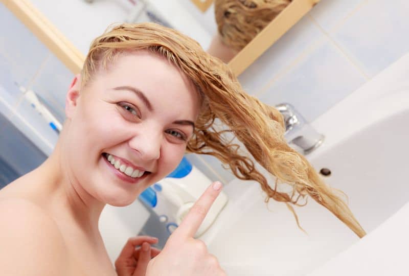 does a bleach bath damage hair - lady doing a bleach bath with wet blonde hair over a sink