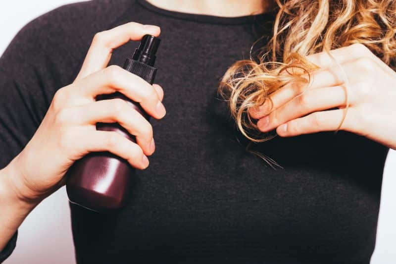 how to make sea salt spray - woman spraying sea salt spray in wavy hair
