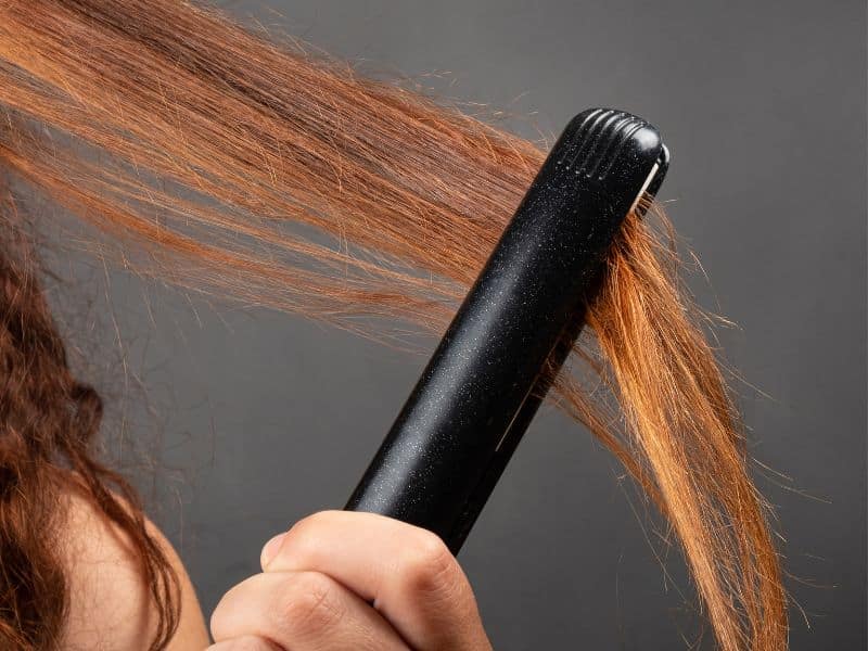 woman with red hair using hot irons