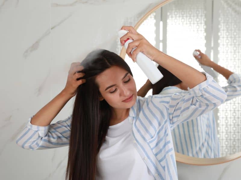 Weekly Hair Care Routine - woman spraying dry shampoo